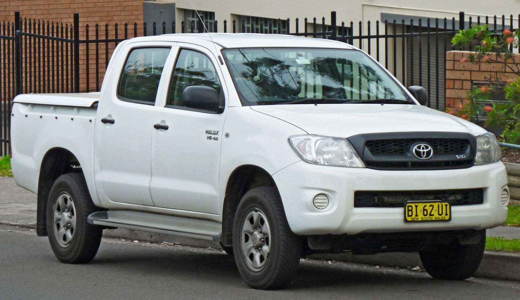 Front-side view of a white double cab pickup with covered cargo bed