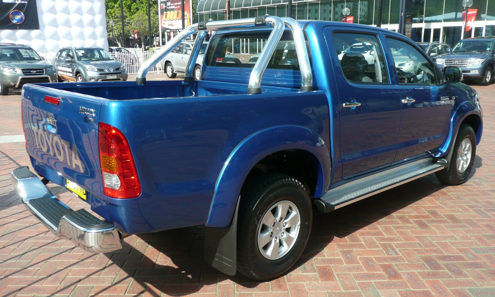 Blue pickup truck with double cab, chrome roll bar, alloy wheels, and step rails