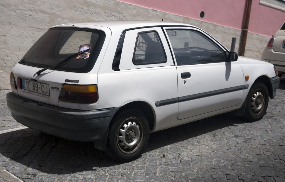 Compact hatchback rear side profile with rear window wiper and steel wheels.