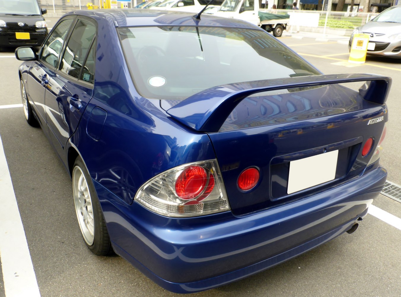 Rear view of blue sedan with distinctive tail lights and rear spoiler.
