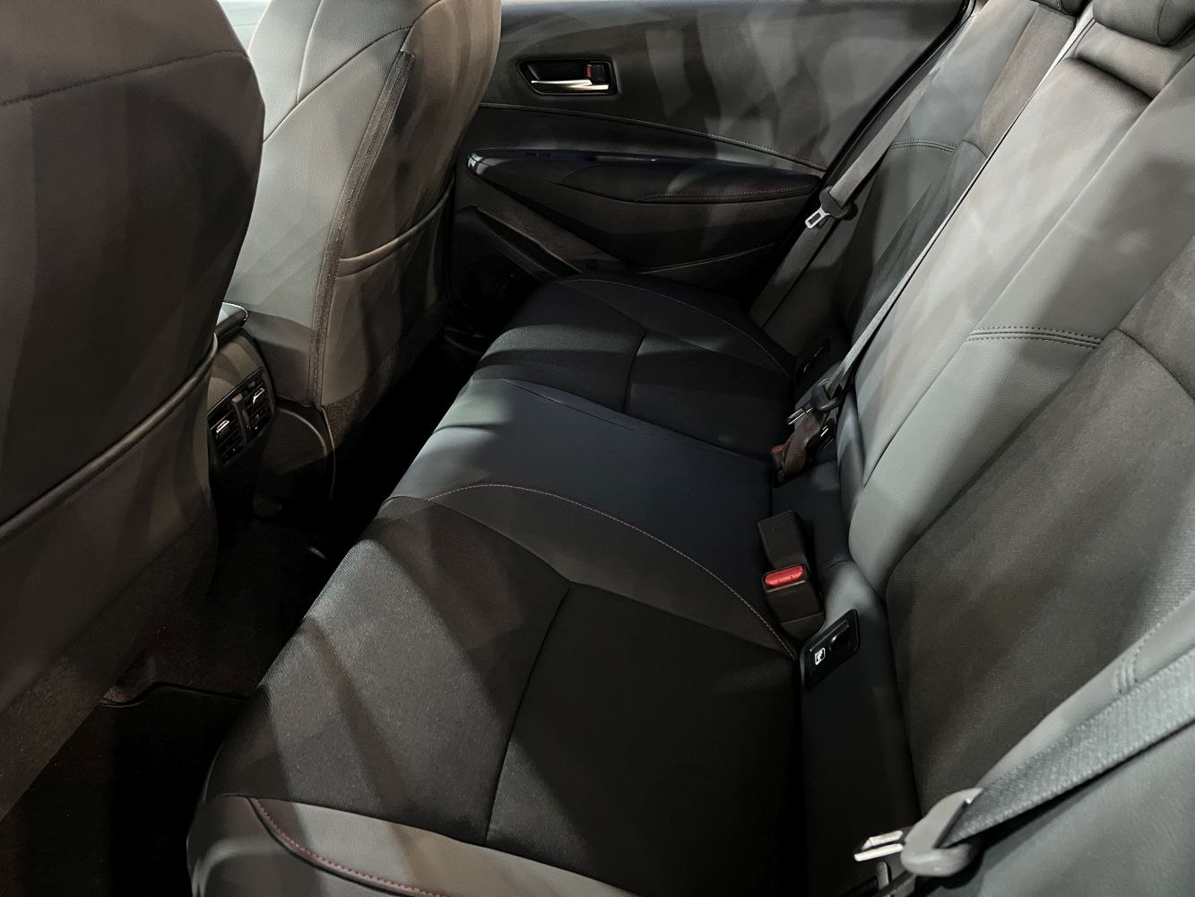 Spacious and modern rear seating with seat belts and door panel.