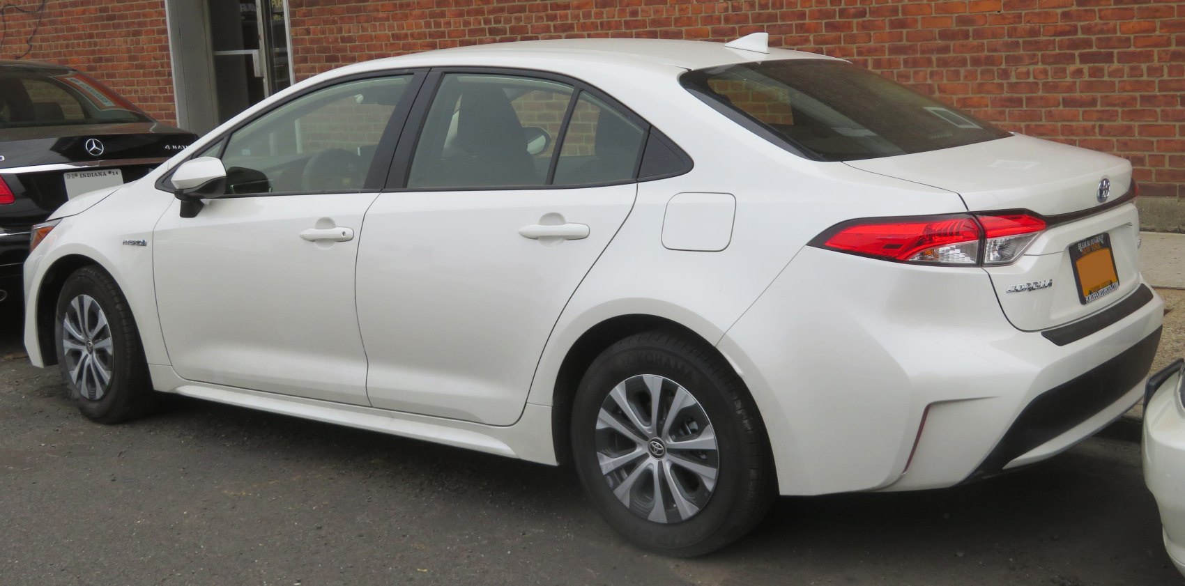 Rear side profile of a white hybrid sedan with sleek taillights and aerodynamic design.