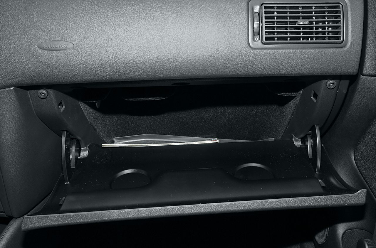 Open glove compartment with dashboard air vent and airbag label