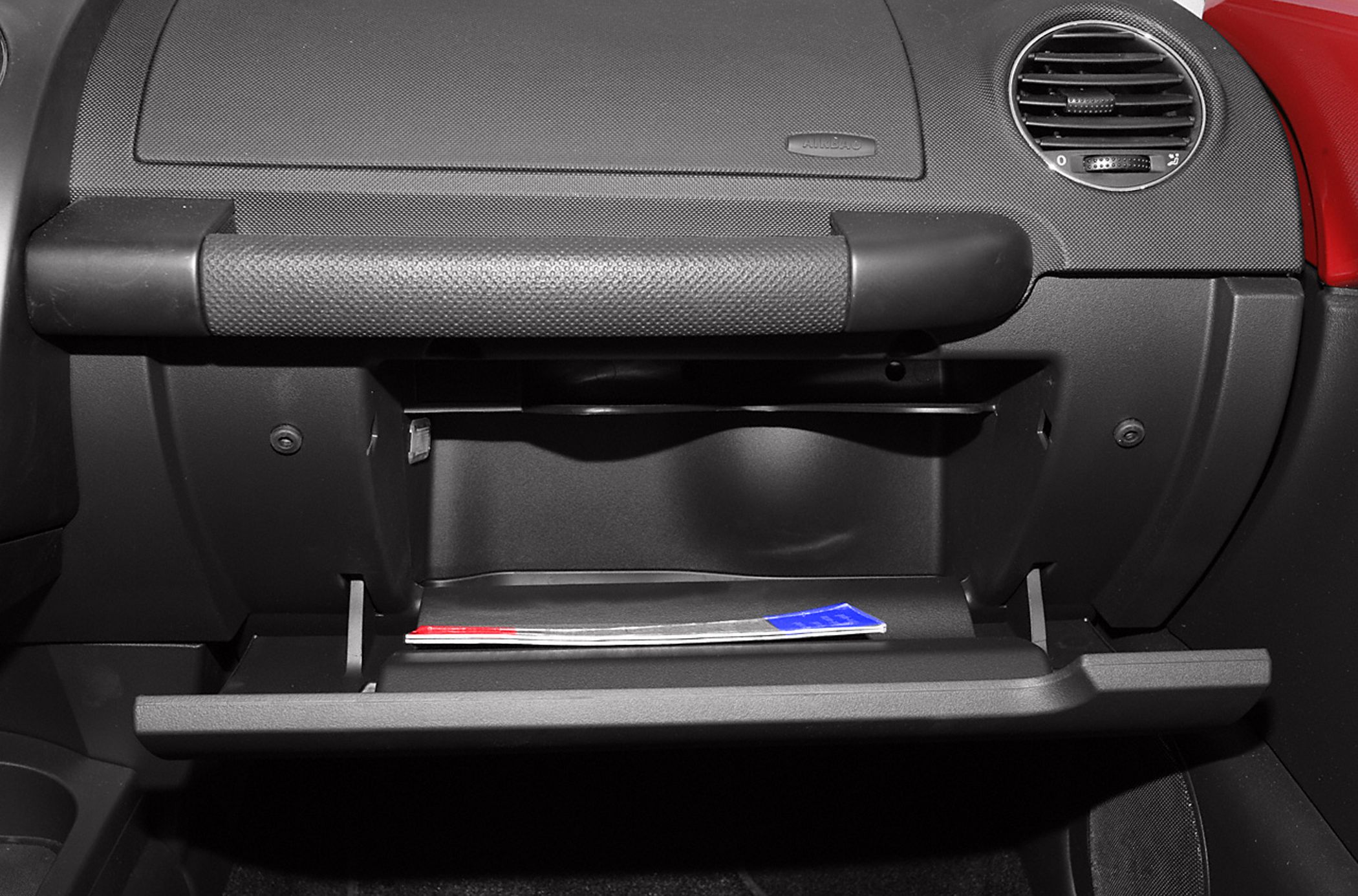 Open glove compartment with textured handle and dashboard air vent