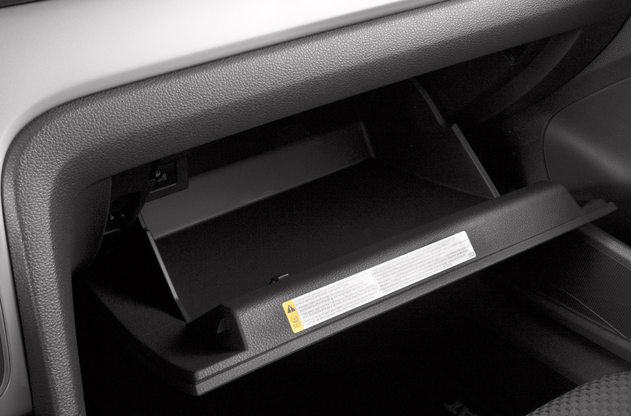 Open glove compartment with textured panel and warning label