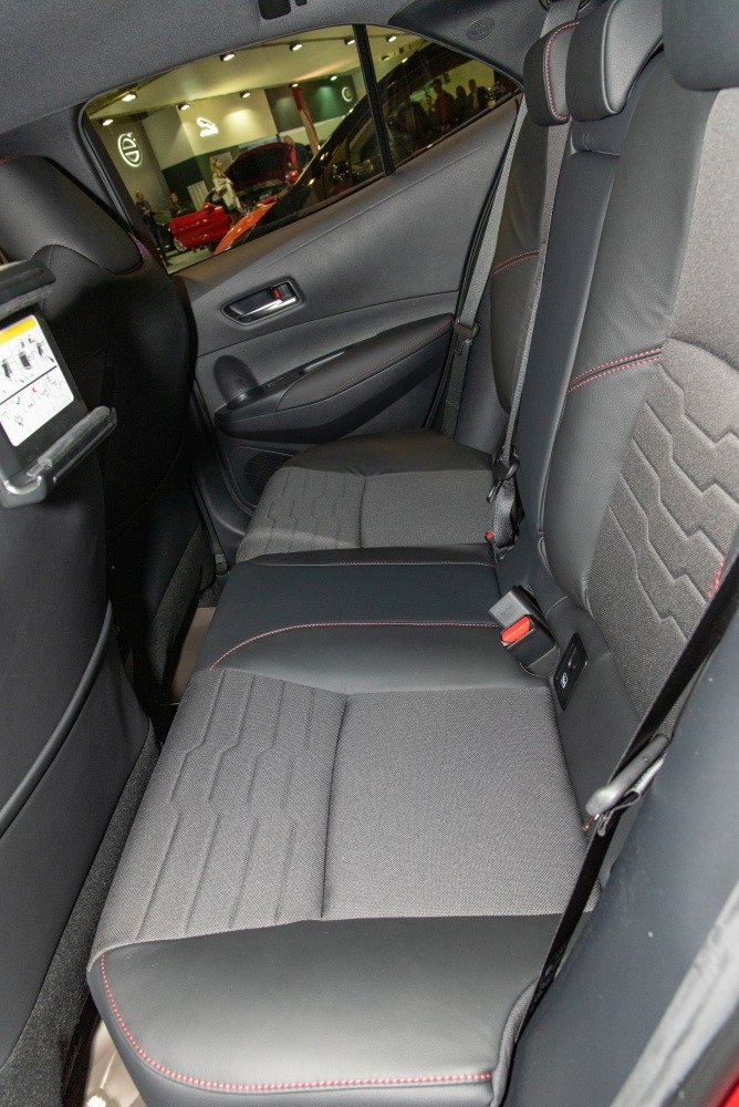 Rear seat upholstery combining fabric and leather with red stitching