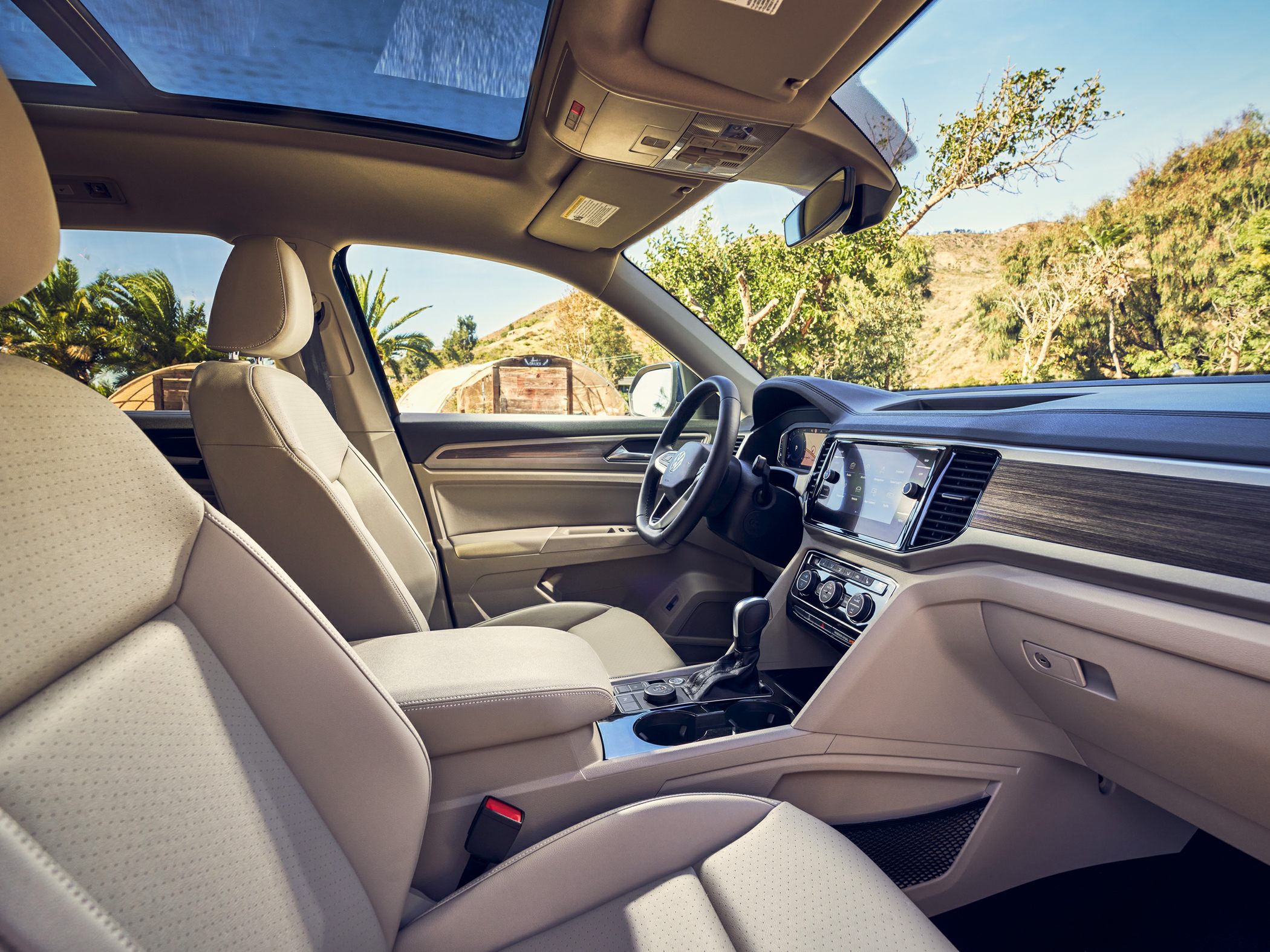 Beige leather seats with panoramic sunroof and modern dashboard inside SUV.