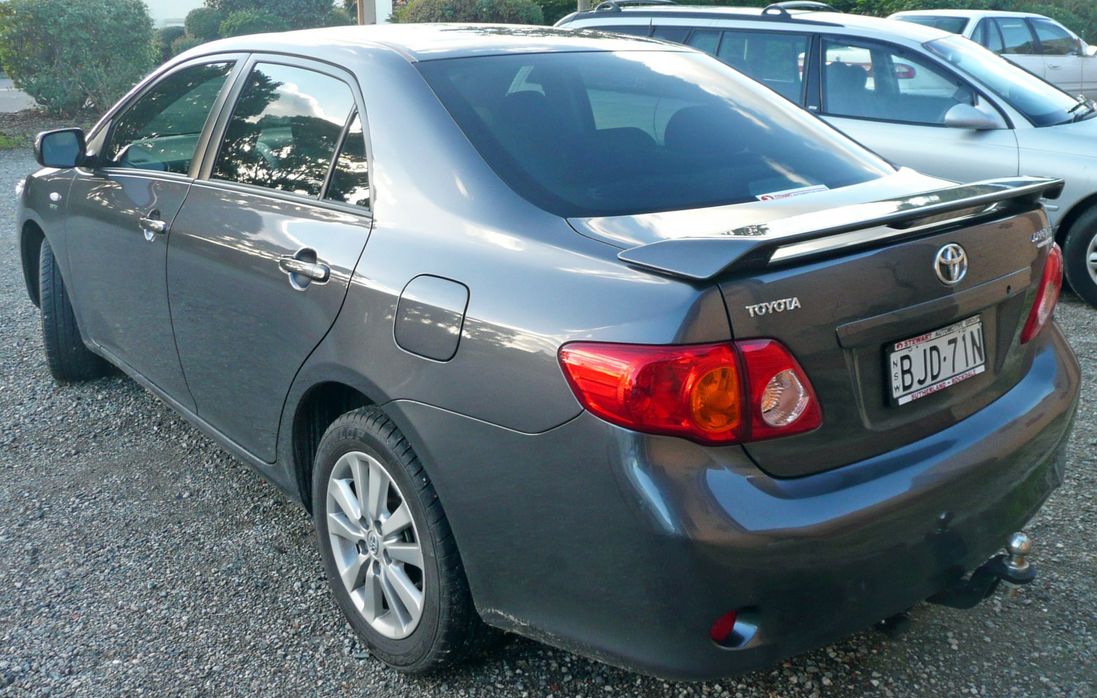 Rear-side view of sedan with spoiler and alloy wheels.
