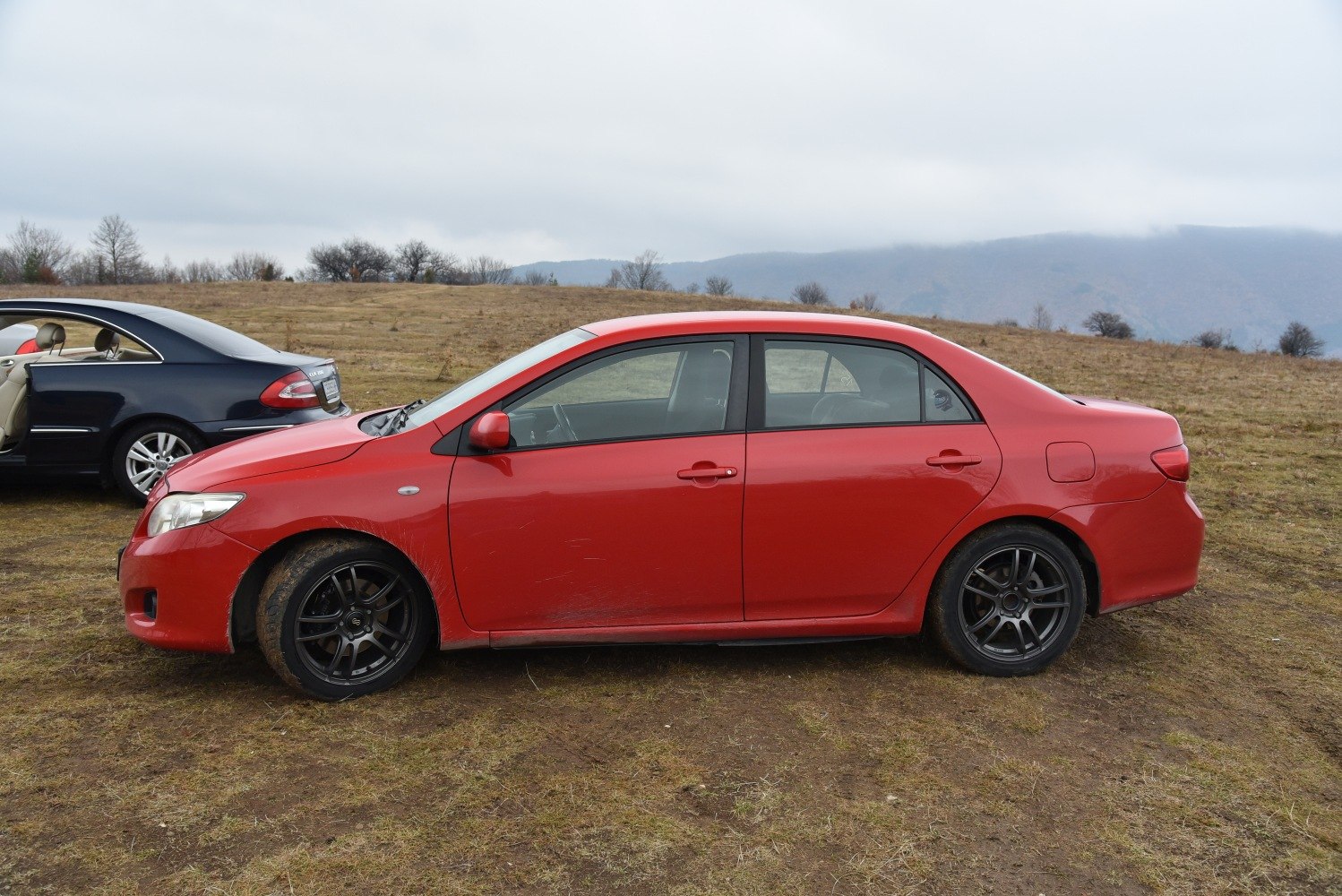 Red sedan side profile with black alloy wheels