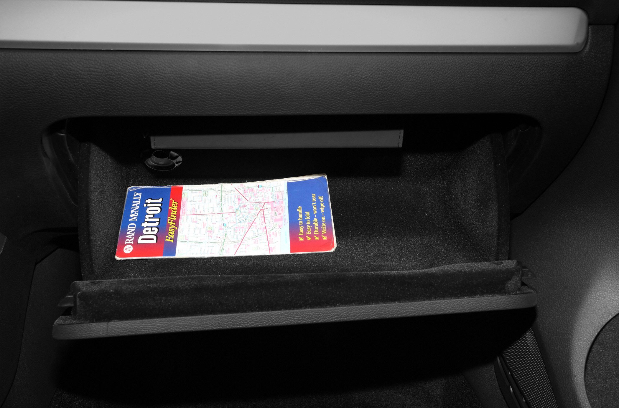 Glove compartment with storage space including a map booklet