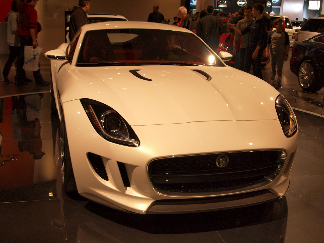 Front view of a white sports coupe with aggressive headlights and hood vents