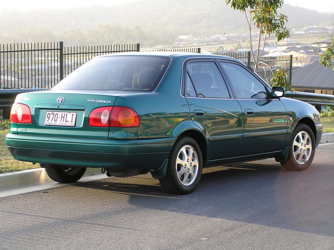Rear and side view of green sedan with distinctive taillights and alloy wheels
