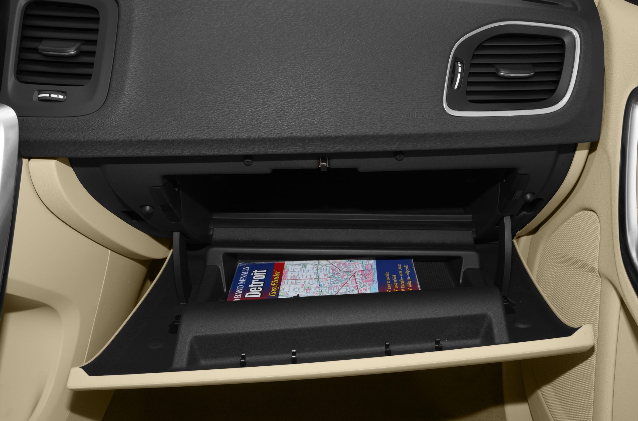 Glovebox storage compartment open with map inside on passenger side.