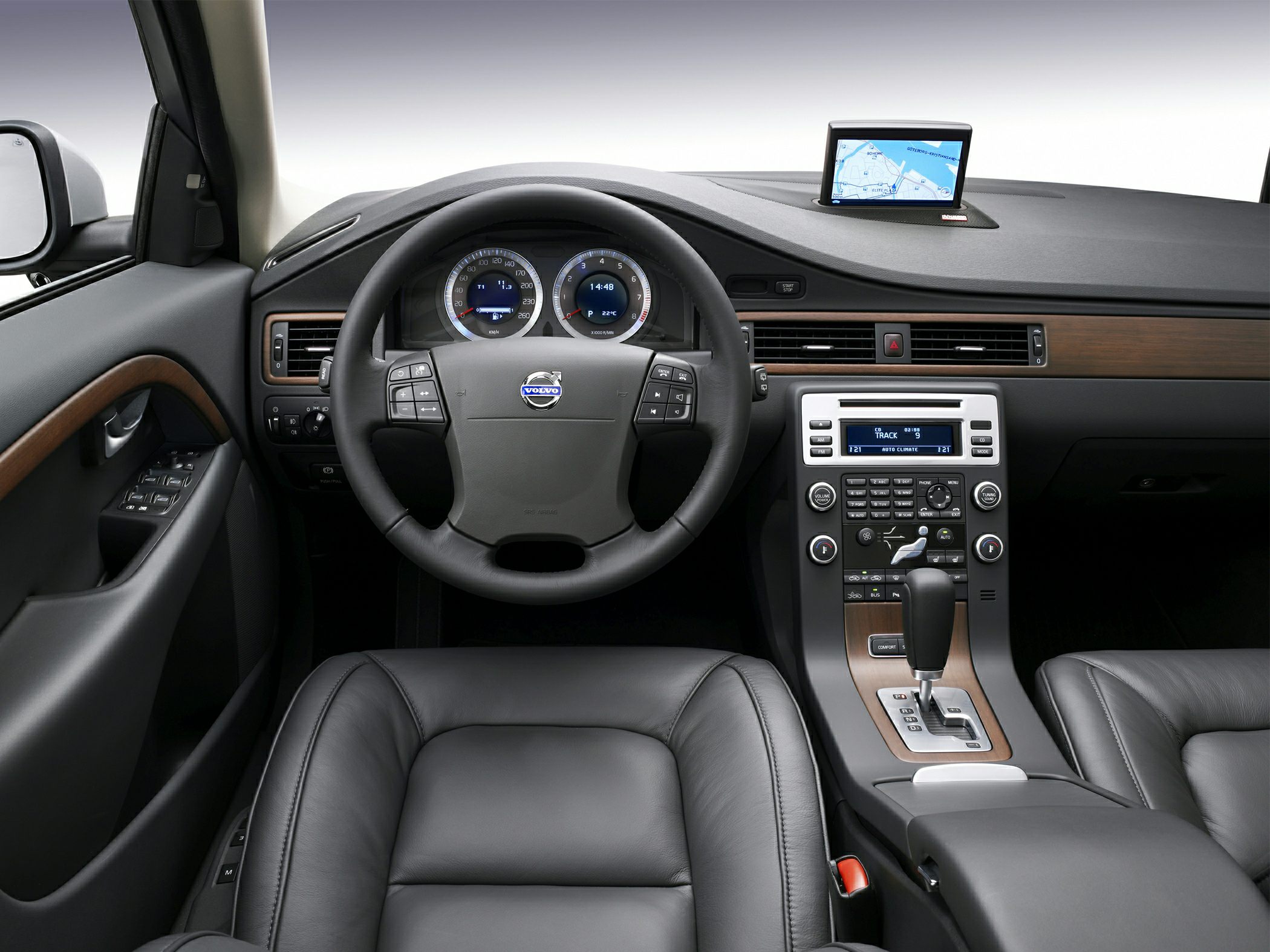 Dashboard and steering wheel with navigation system and wood trim.