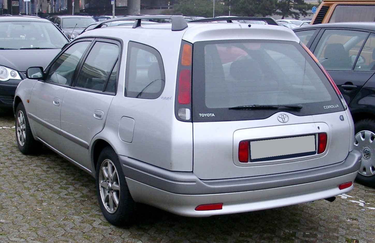 Rear view of a silver station wagon showing tail lights and roof rails