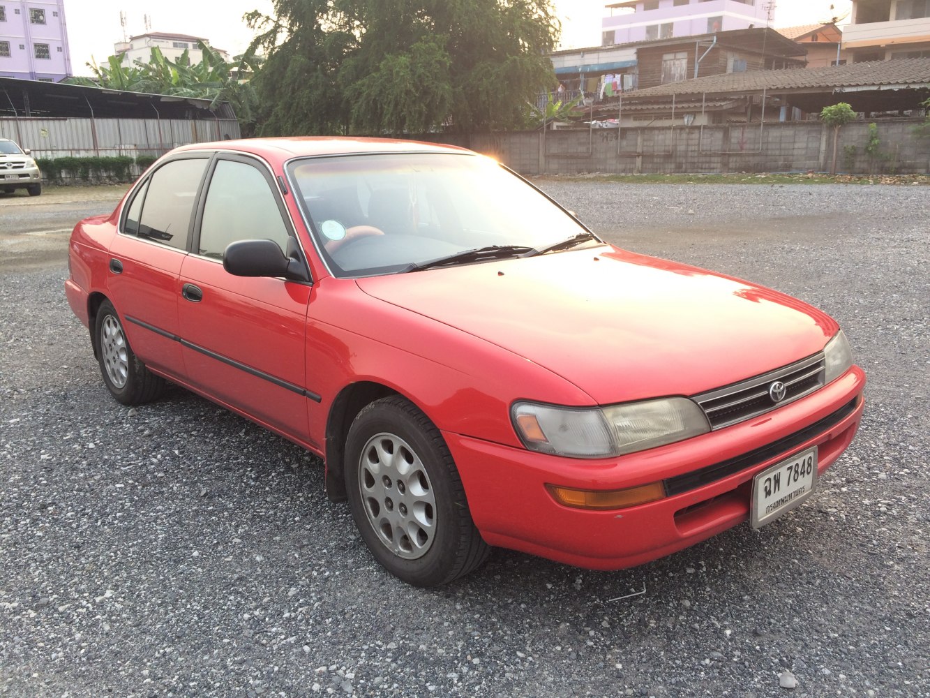 Red sedan with rounded headlights and multi-hole alloy wheels