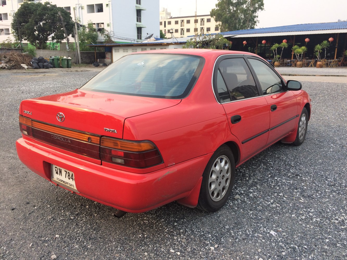 Rear and side view showing tail lights, rear bumper, and wheel of red sedan
