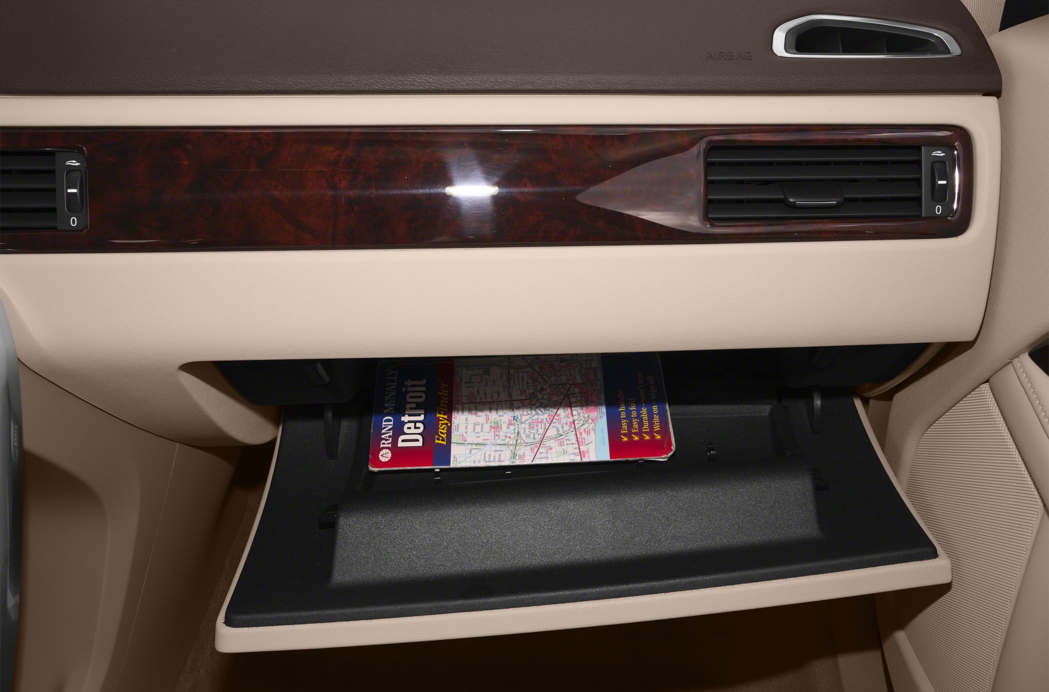 Open glove box with wood panel trim and beige interior upholstery.