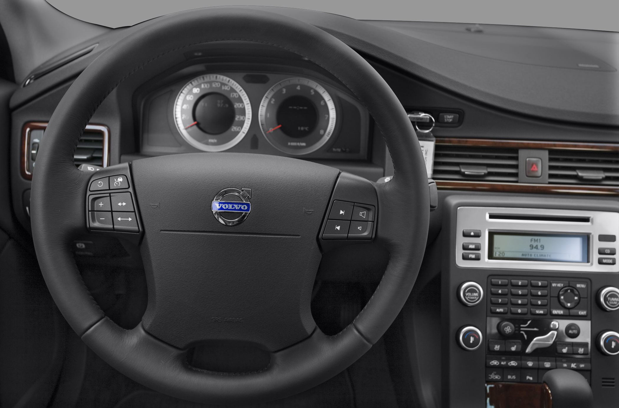Steering wheel with control buttons and dashboard instrument cluster, center console with controls