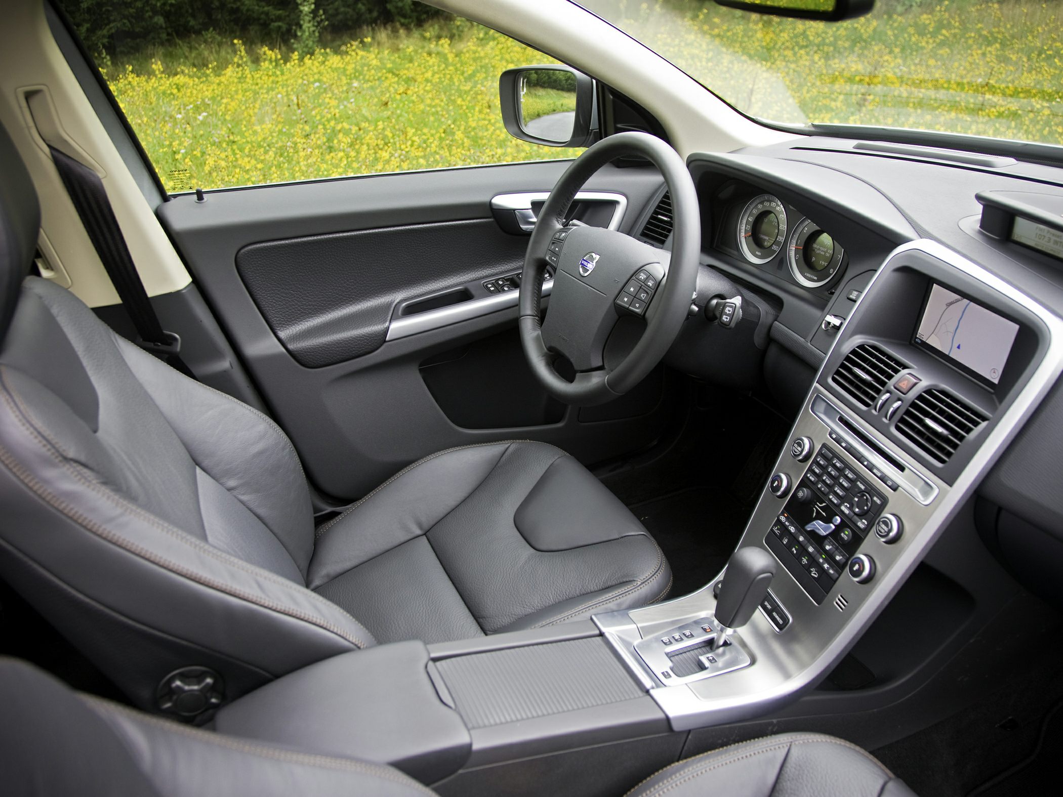 Car interior with dashboard, steering wheel, leather seat, and navigation screen
