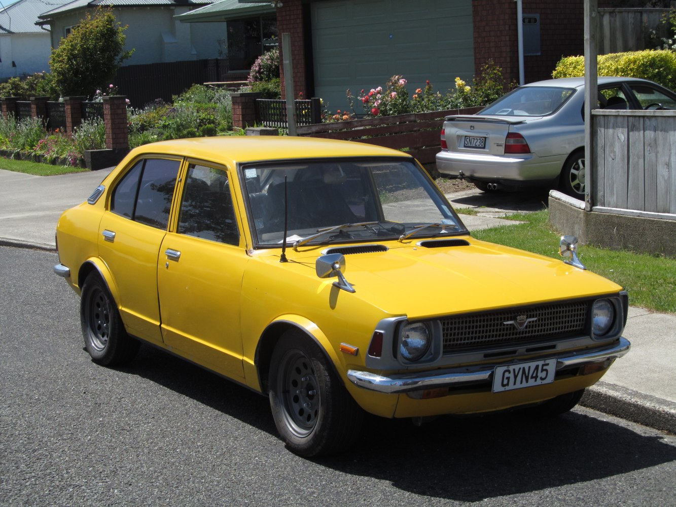 Yellow 4-door sedan with hood scoops and fender-mounted mirrors