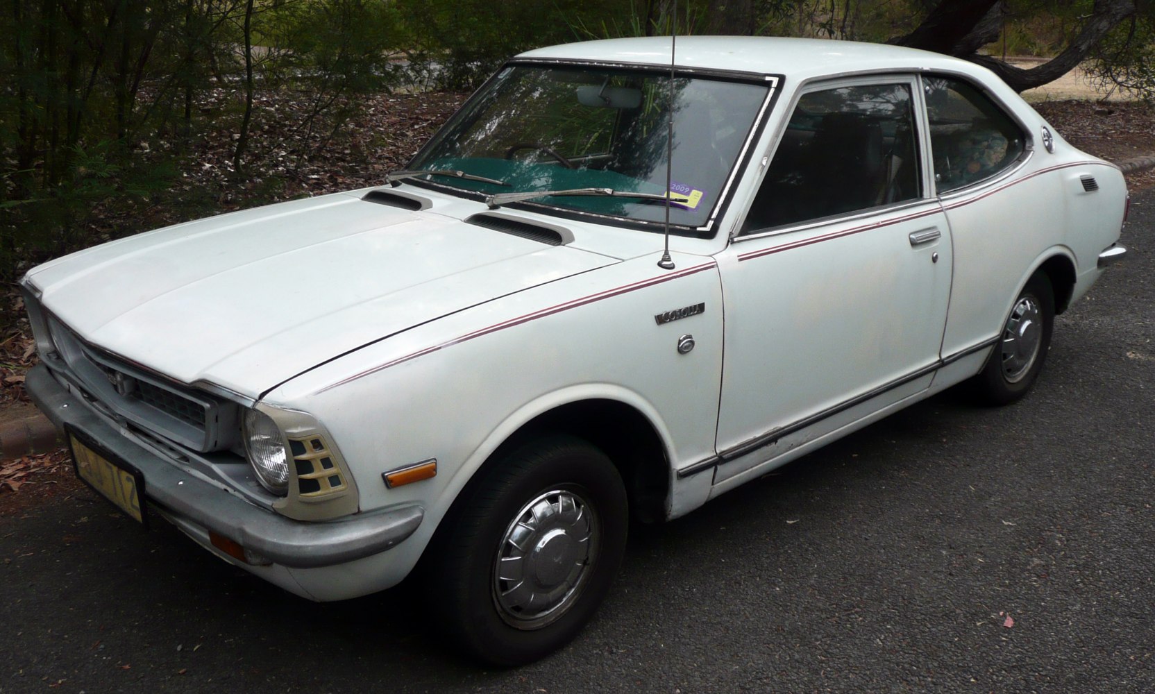 1970s two-door sedan with front vents and chrome hubcaps