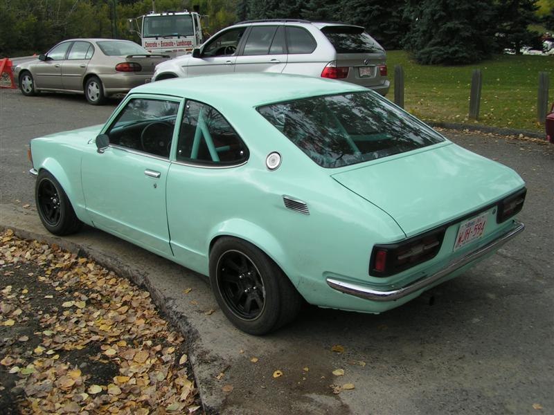 Light blue two-door coupe with black wheels rear-left view