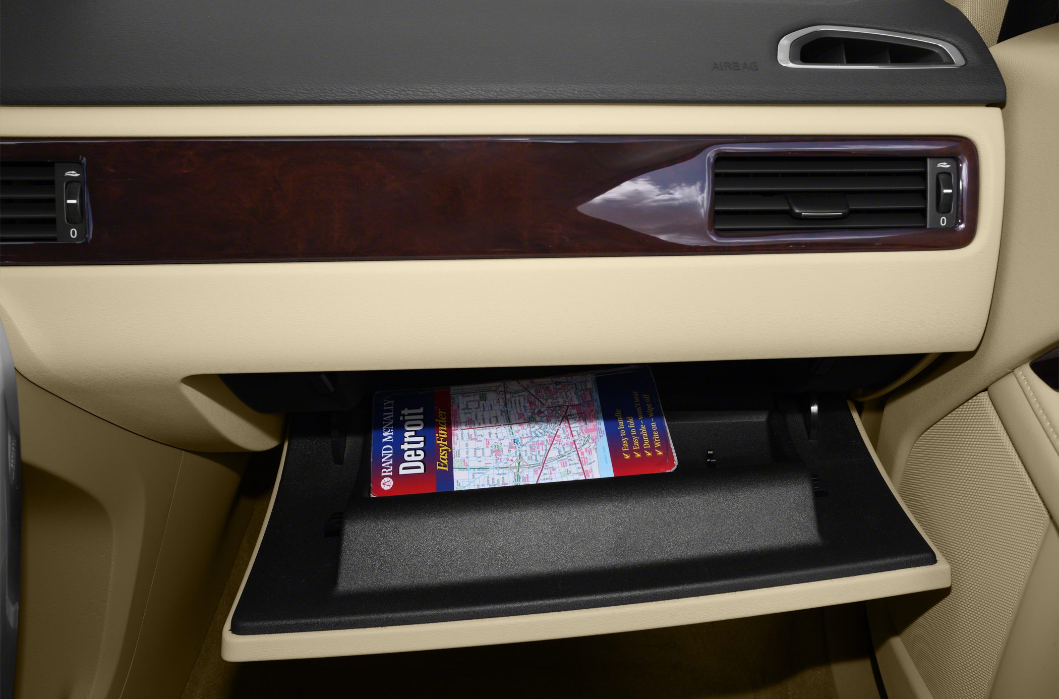 Beige car glove box with wood panel trim and dashboard air vents