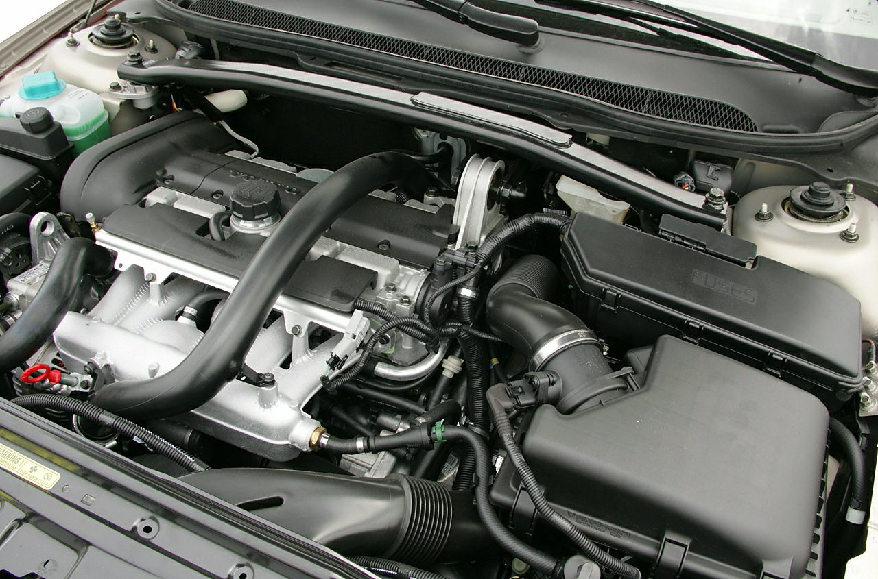 Engine bay with visible air intake, hoses, fuse box, and wiring