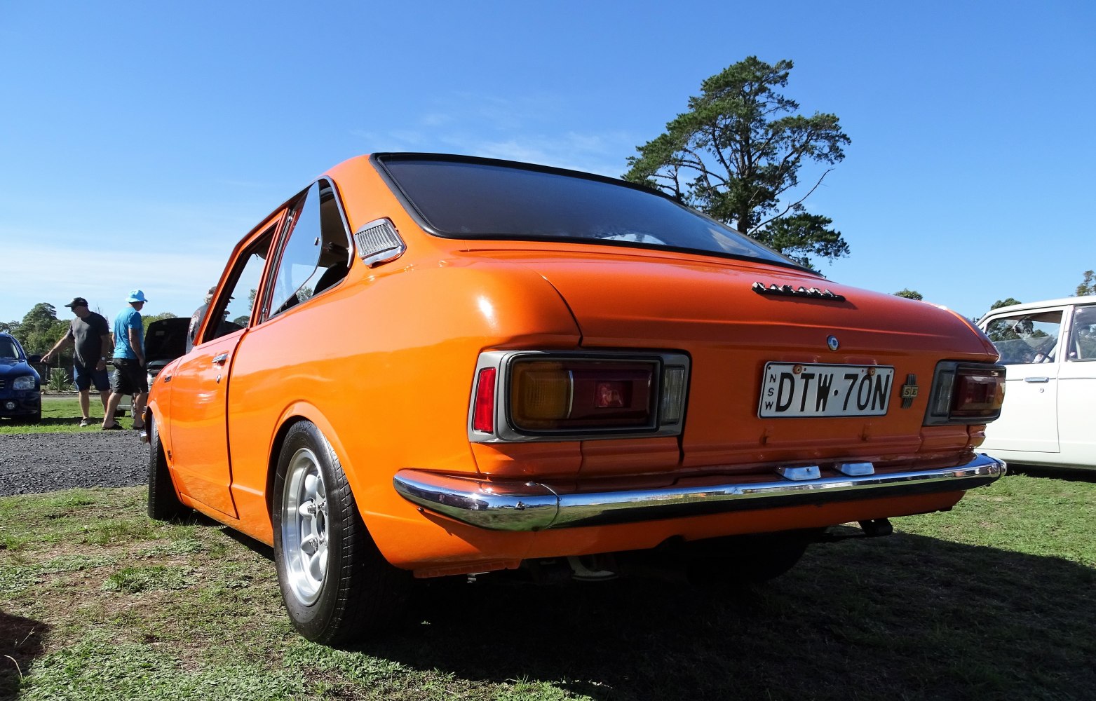 Bright orange classic 2-door sedan rear with rectangular tail lights and chrome bumper.