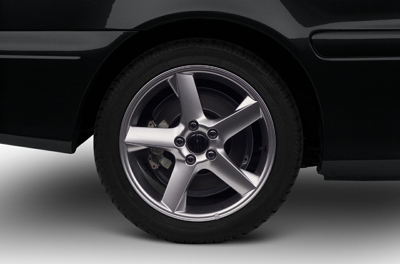Close-up of five-spoke alloy wheel and tire with brake disc behind.