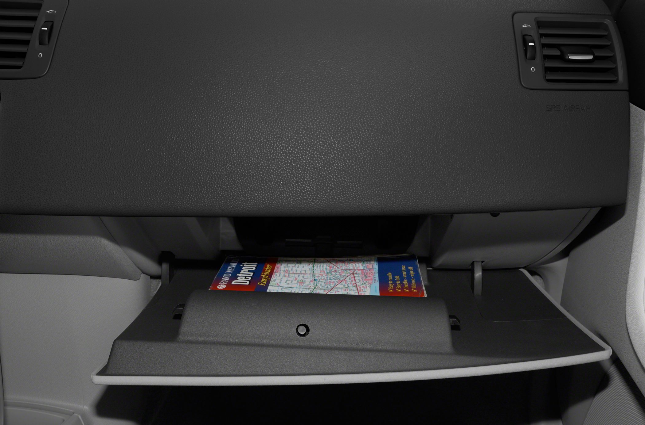 Car dashboard glovebox open with a map inside