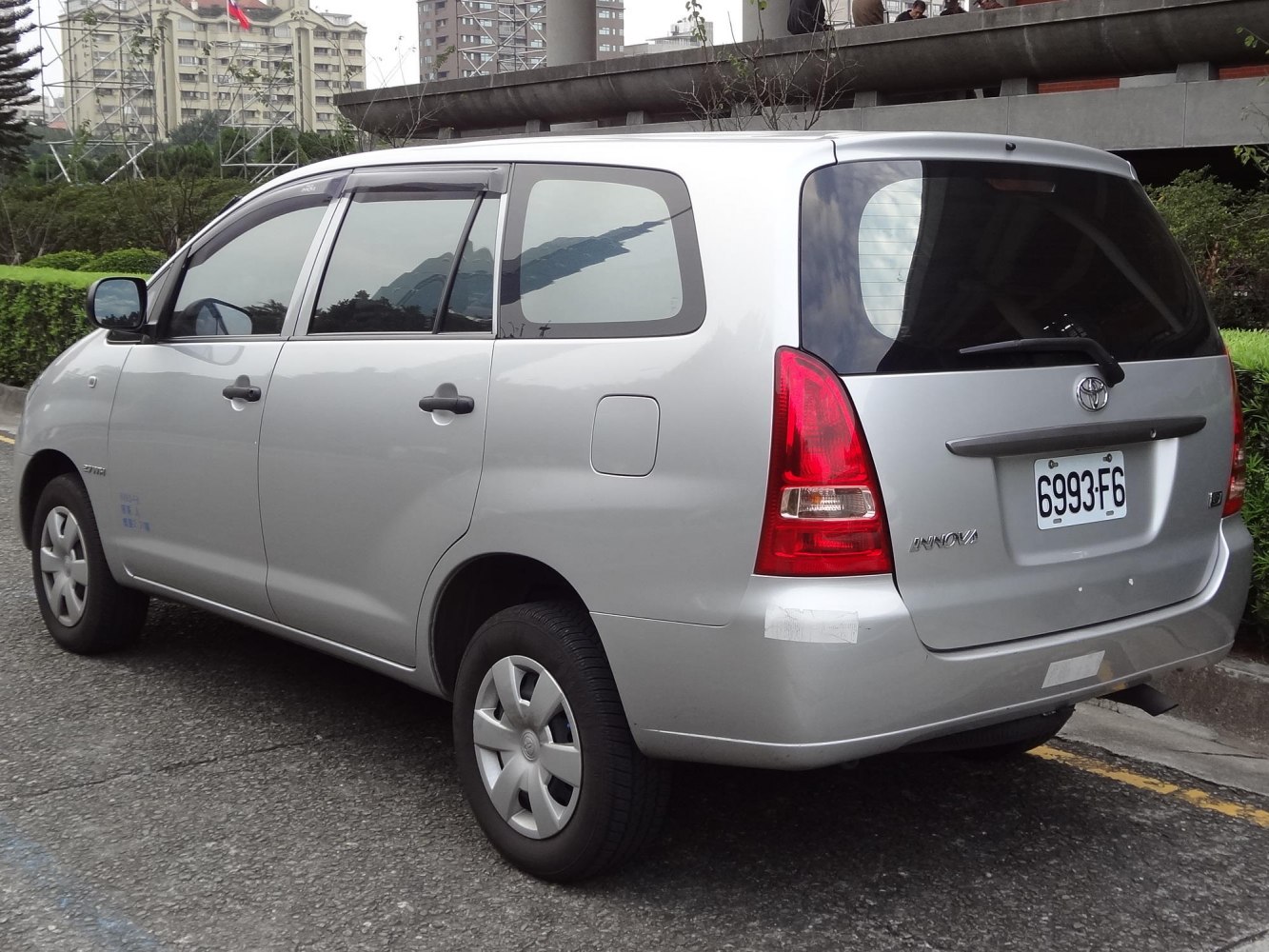 Rear and side view of silver multi-purpose vehicle with tail lights and dark tinted windows.