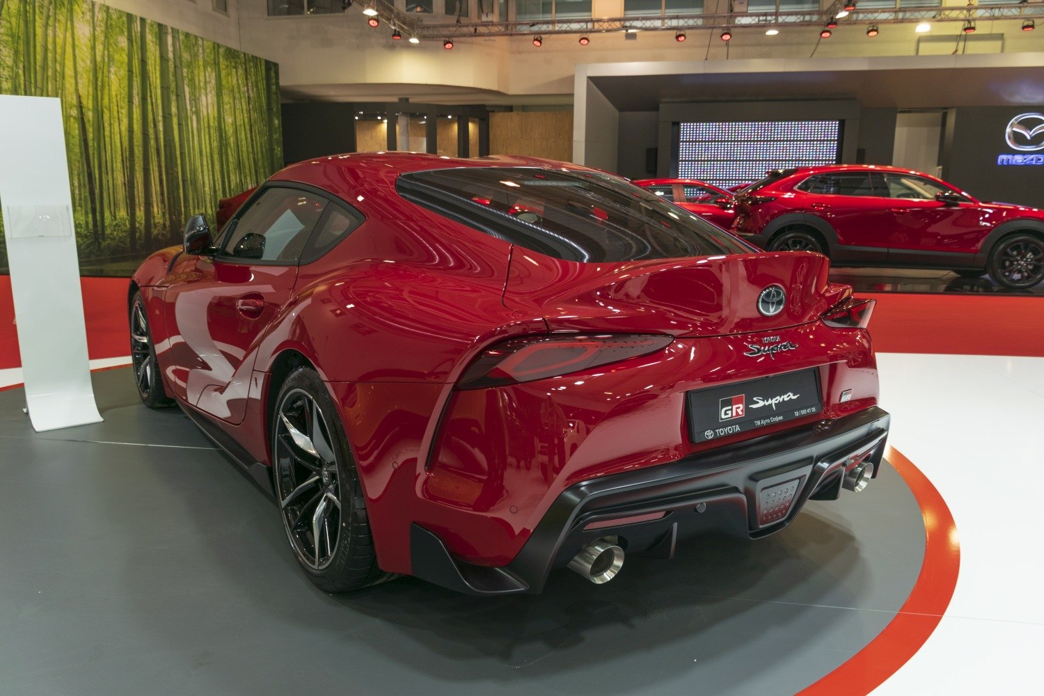 Sleek rear profile of a red sports coupe with dual exhausts and sharp tail lights.