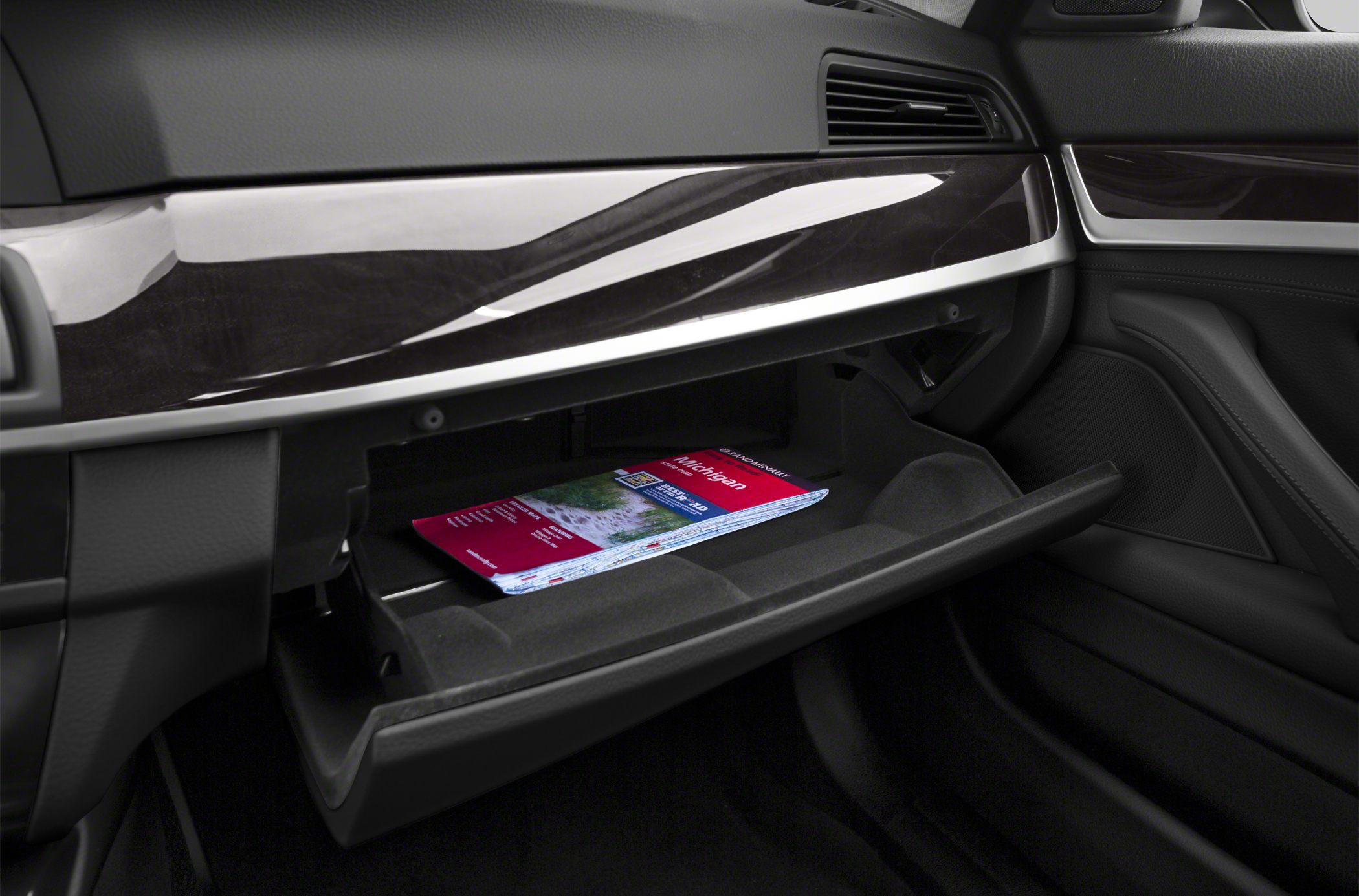 Open glove compartment with a brochure inside and dashboard trim