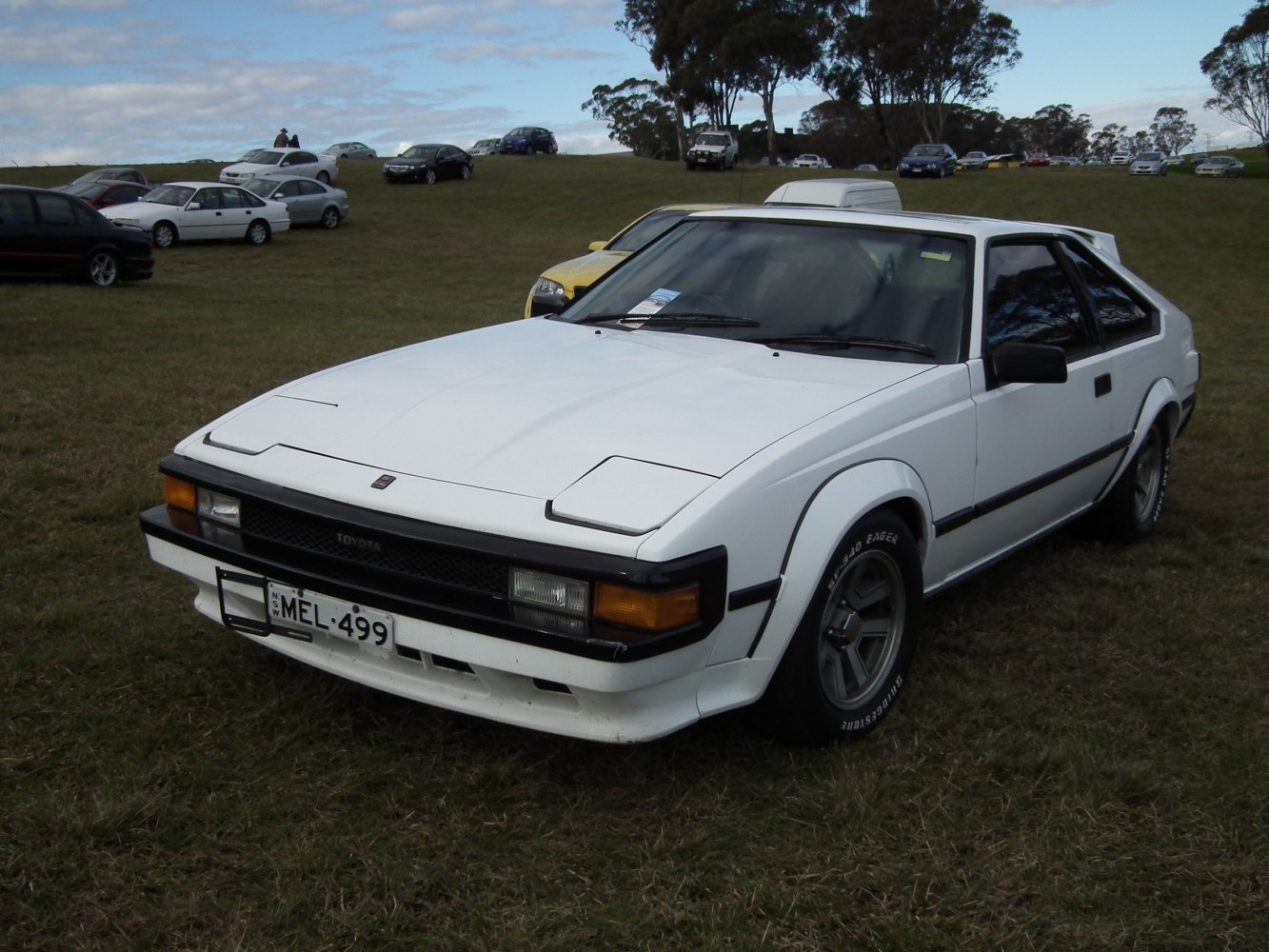 White vintage sports coupe with pop-up headlights and angular design.