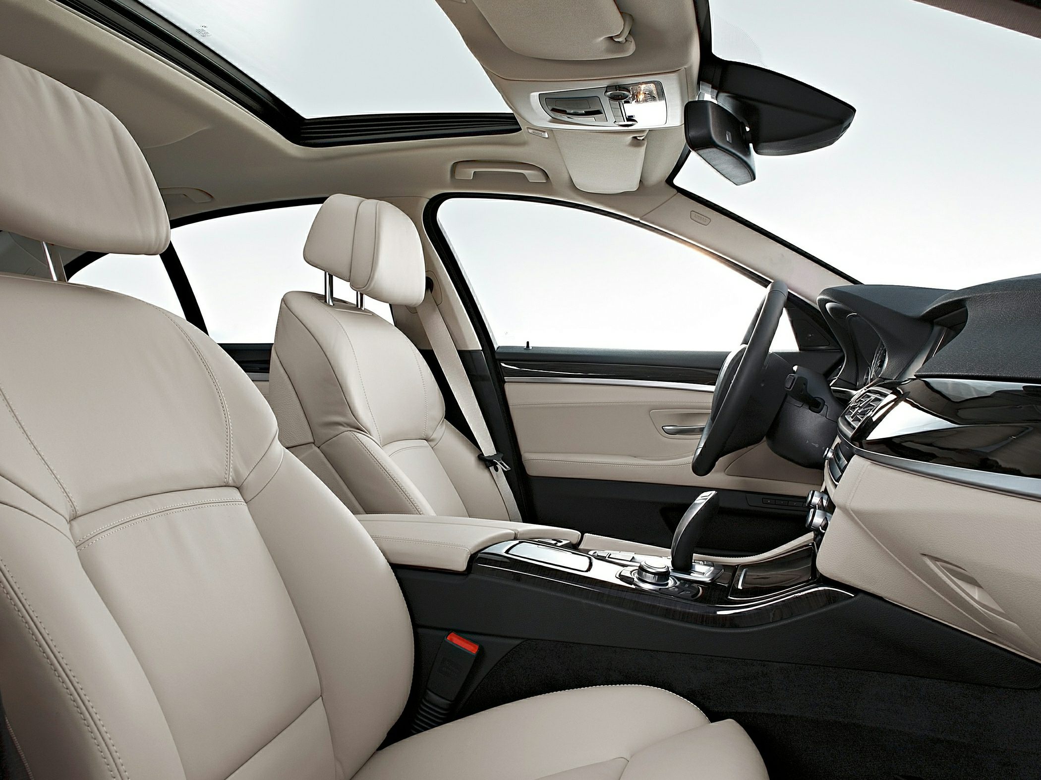 Beige leather seats and panoramic sunroof inside luxury sedan.