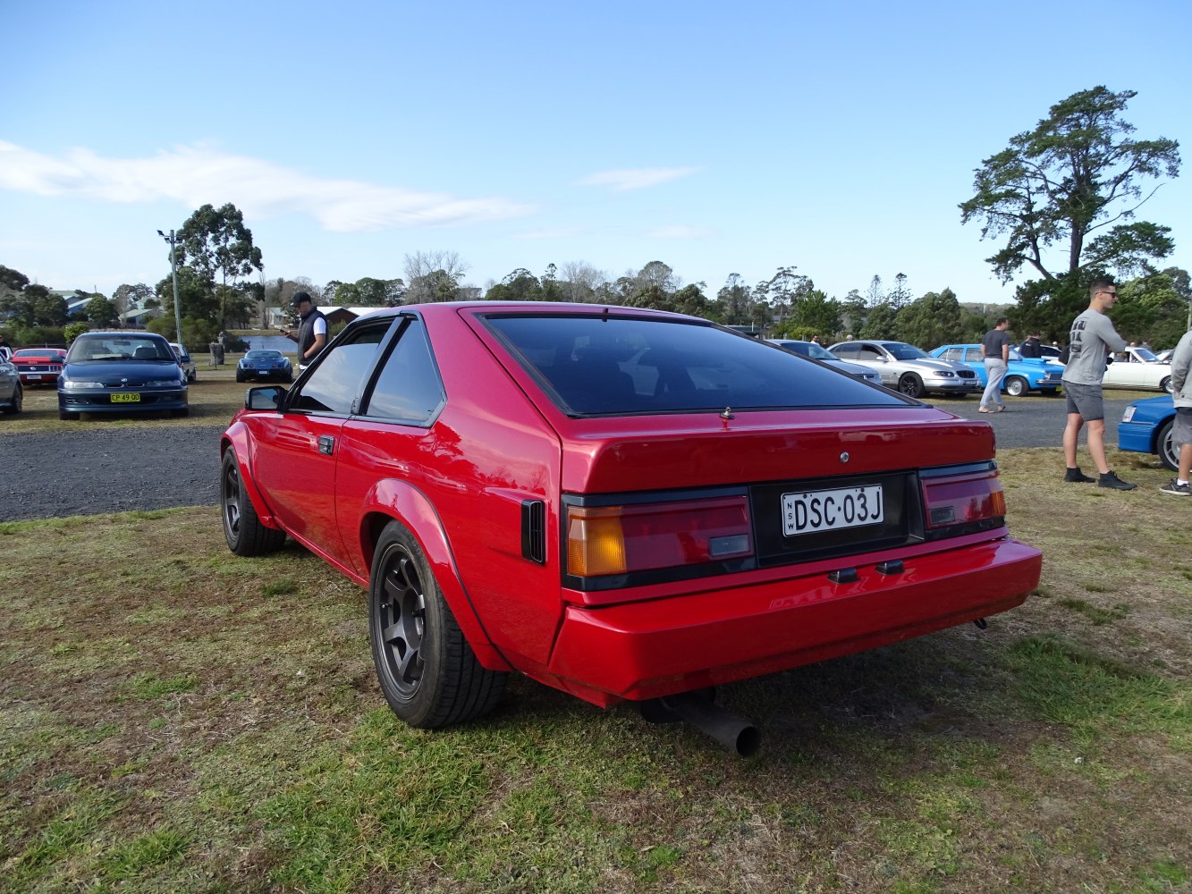 Rear side view of red classic sports coupe with wide tires and tinted windows