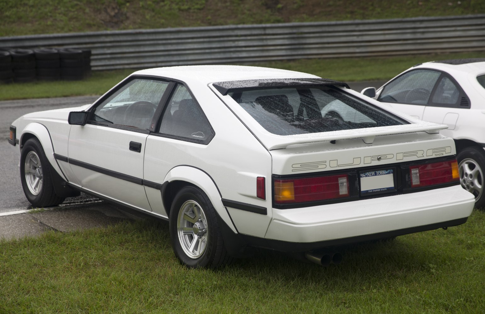 Rear side view with spoiler and dual exhaust of classic 1980s sports coupe
