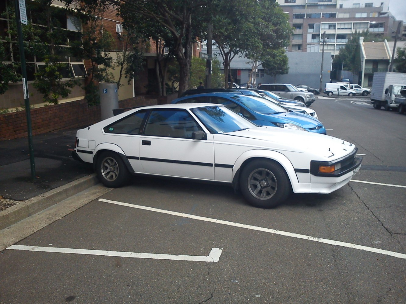 White vintage coupe with pop-up headlights and distinctive sporty design.