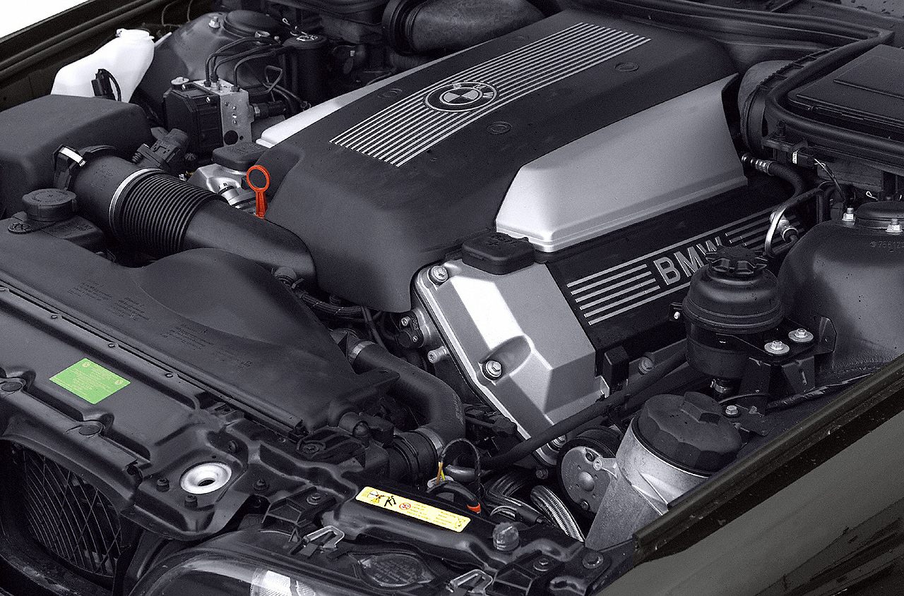 Close-up of an engine bay with BMW-branded engine cover and surrounding components
