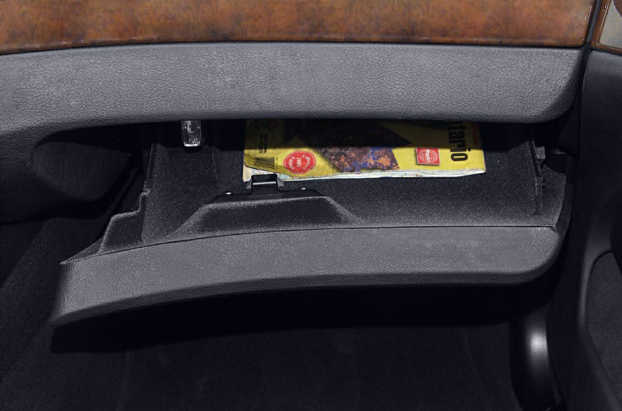 Open glove box with wood and black trim interior