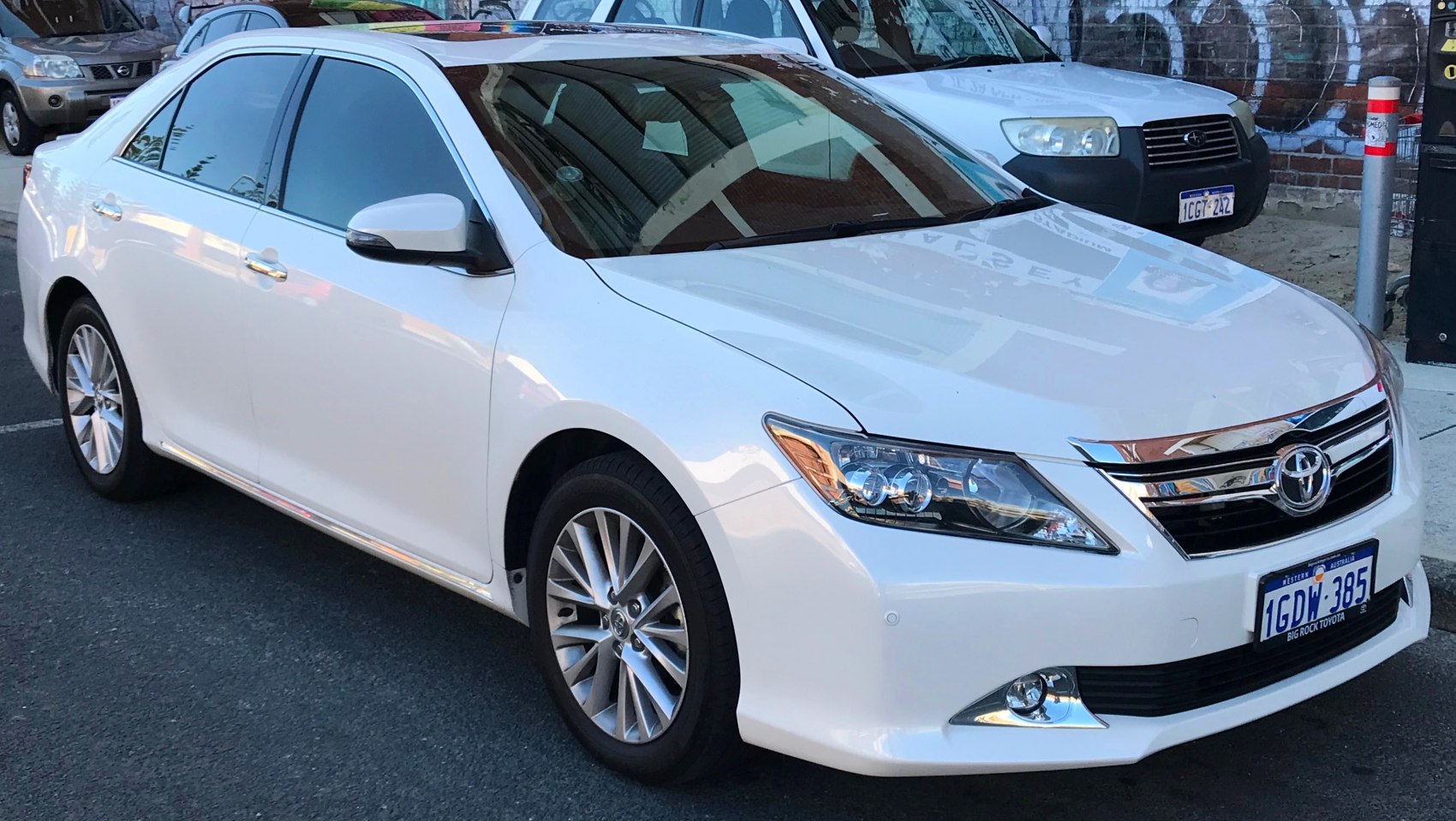 White mid-size sedan with modern headlamps and alloy wheels