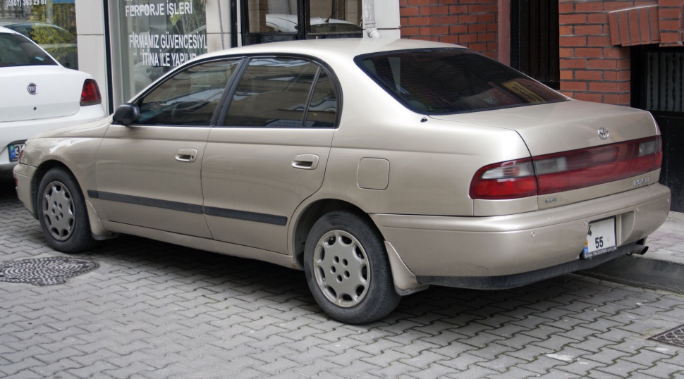 Side and rear view of a beige four-door sedan with classic 1990s styling.