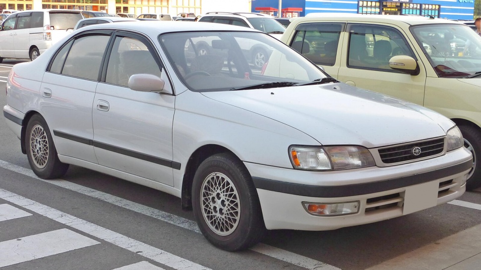 White four-door sedan with classic mesh alloy wheels and black side trim
