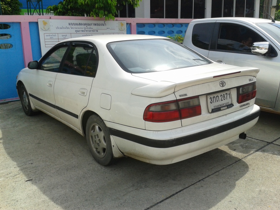 Rear side view with spoiler and classic taillights on a 1990s sedan