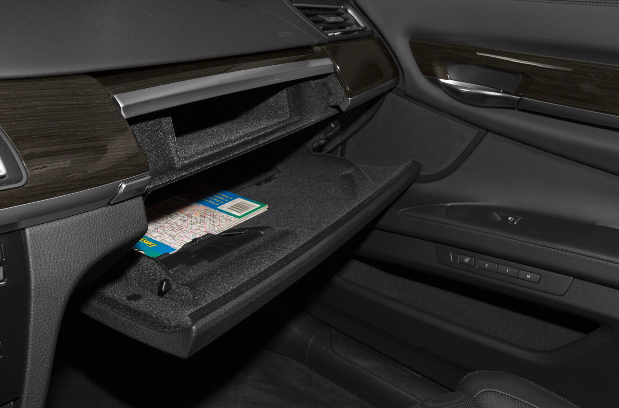 Open glove compartment with map and wood trim in luxury car interior