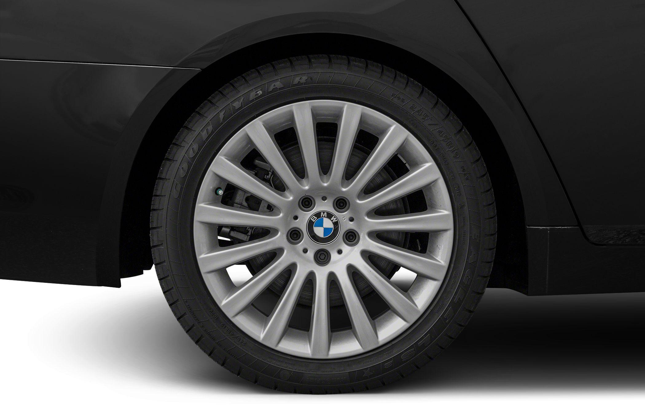 Silver multi-spoke alloy wheel with tire mounted on a black vehicle.