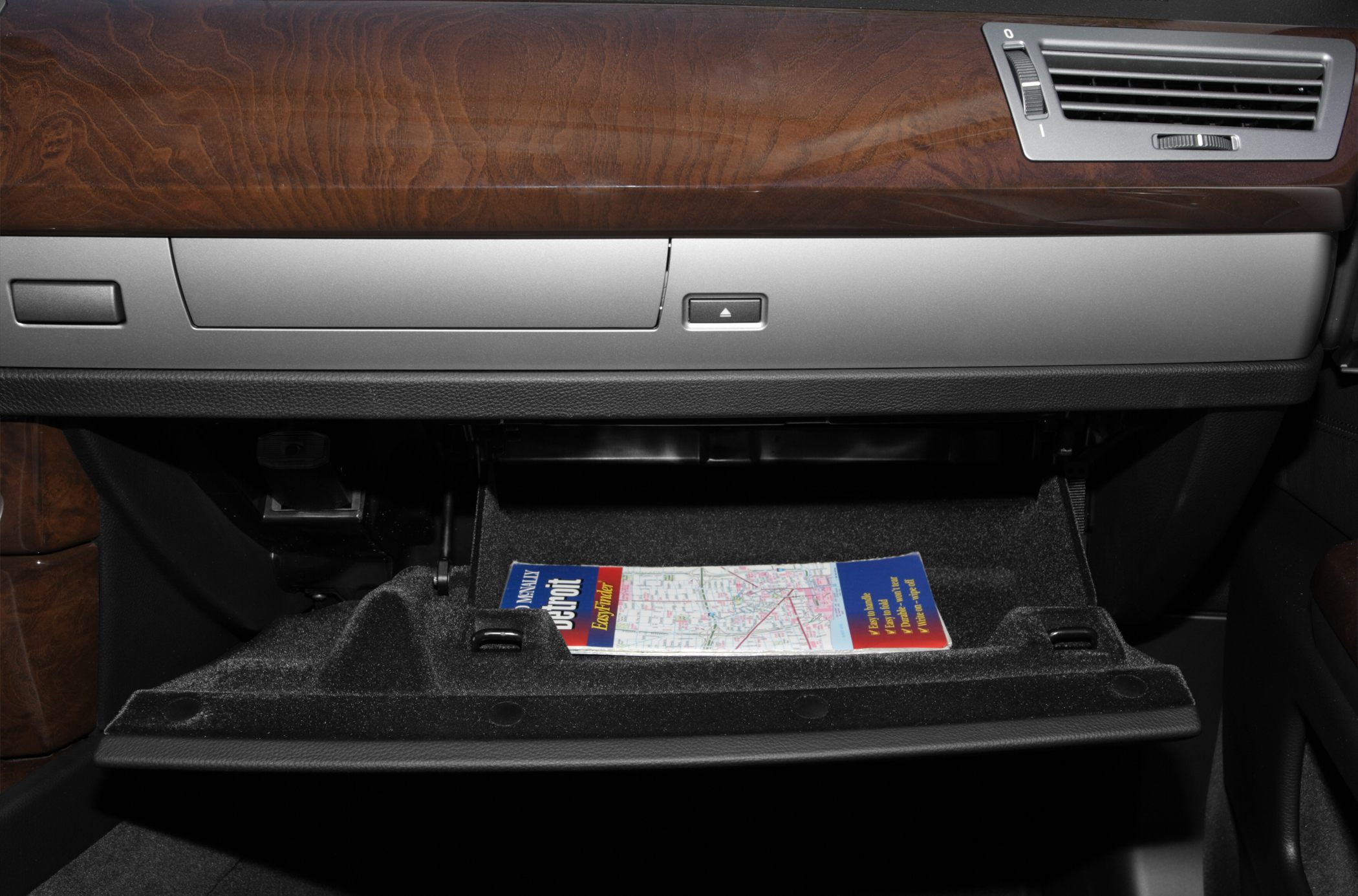 Glove compartment with wood trim and air vent in luxury car interior