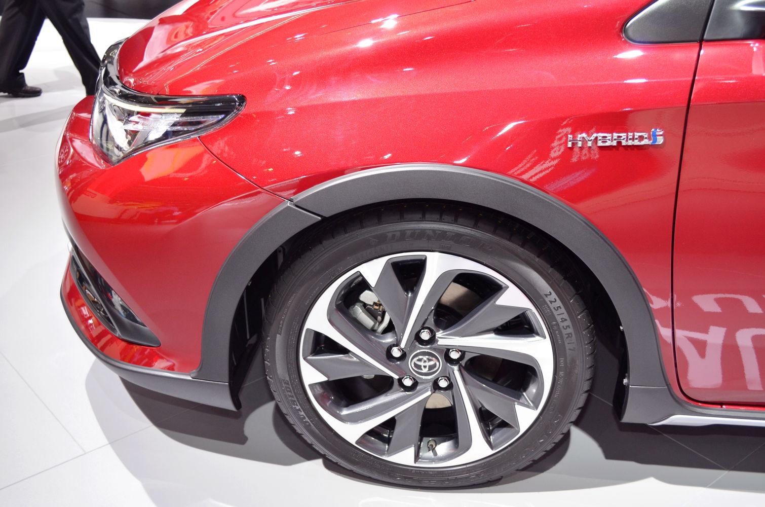 Front wheel arch, alloy wheel, and hybrid badge on a red vehicle